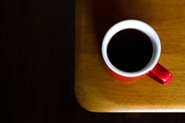 Kahve dükkanında sabah ışığıyla ahşap masanın üstünde sıcak americano sade kahvesi. Çalışma saatlerinde dinlenmek için kahve molası.