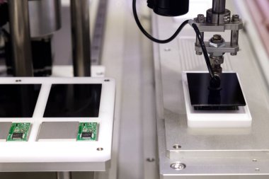 Üretim hattında çalışan ve yeni yenilikçi ve yüksek teknoloji akıllı telefon fabrikasında akıllı telefon ekranları monte eden vakumlu otomatik robot kolu..