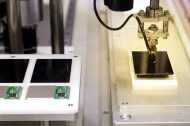 Üretim hattında çalışan ve yeni yenilikçi ve yüksek teknoloji akıllı telefon fabrikasında akıllı telefon ekranları monte eden vakumlu otomatik robot kolu..