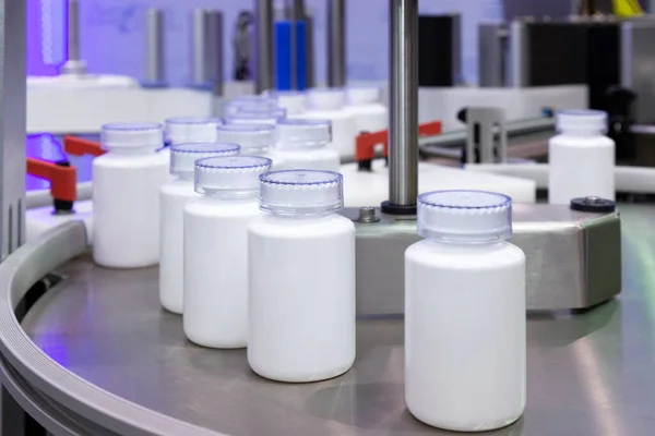 Fabrikadaki dolum makinesinin üretim hattındaki beyaz plastik şişe. seçici odak.