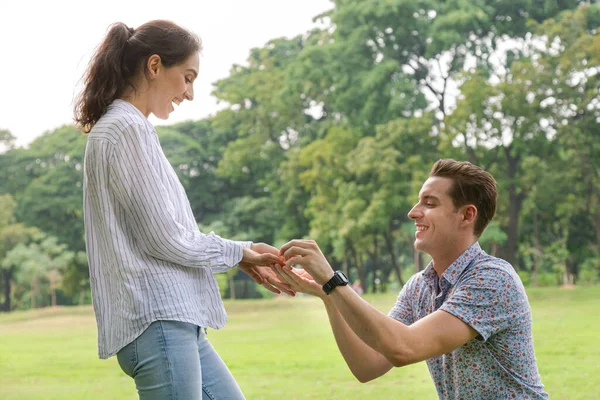 Surpresa Jovem Mulher Sorrindo Enquanto Seu Casamento Namorado Propondo Parque — Fotografia de Stock