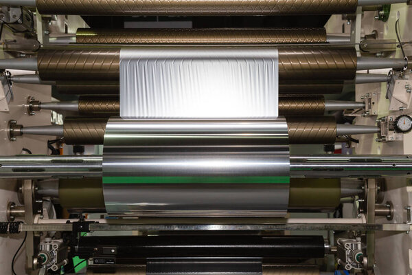 рулон алюминиевой фольги для упаковки пищевых продуктов на автоматической упаковочной машине на заводе пищевых продуктов. промышленная и технологическая концепция. 
