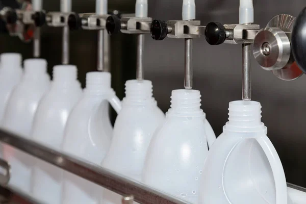 Fabrikadaki dolum makinesinin üretim hattındaki beyaz plastik galon veya şişe. Seçici odaklanma. sanayi ve teknoloji kavramı.