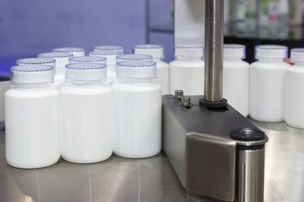 İlaç ya da kozmetik beyaz plastik şişe, sağlık hizmetleri üretiminde dolum makinesinde taşıyıcı bandın üretim hattında.
