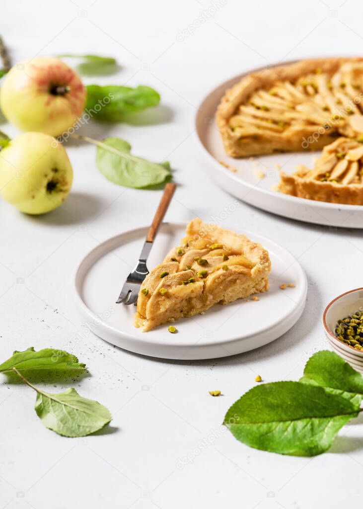 Piece of tasty homemade apple tart with green pistachios ready to eat. Healthy sweet food concept.