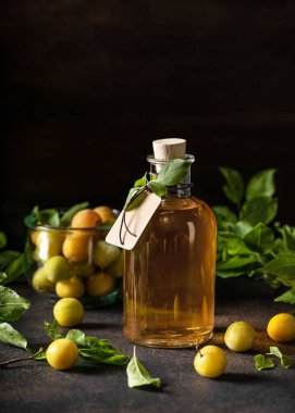 Bir şişe lezzetli sarı erik likörü ya da ahşap masada şarap. Ev yapımı güçlü alkollü içecek. Koyu kırsal tarzı.