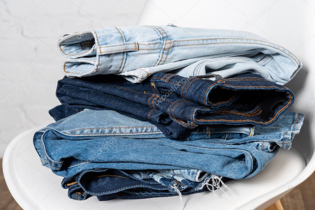 close up view of various jeans stacked on chair