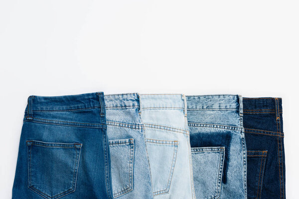 горизонтальный ряд различных синих джинсов, изолированных на белом, вид сверху