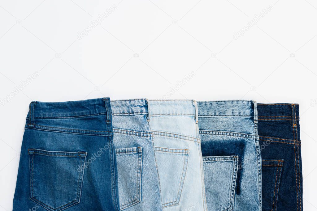 horizontal row of different blue jeans isolated on white, top view