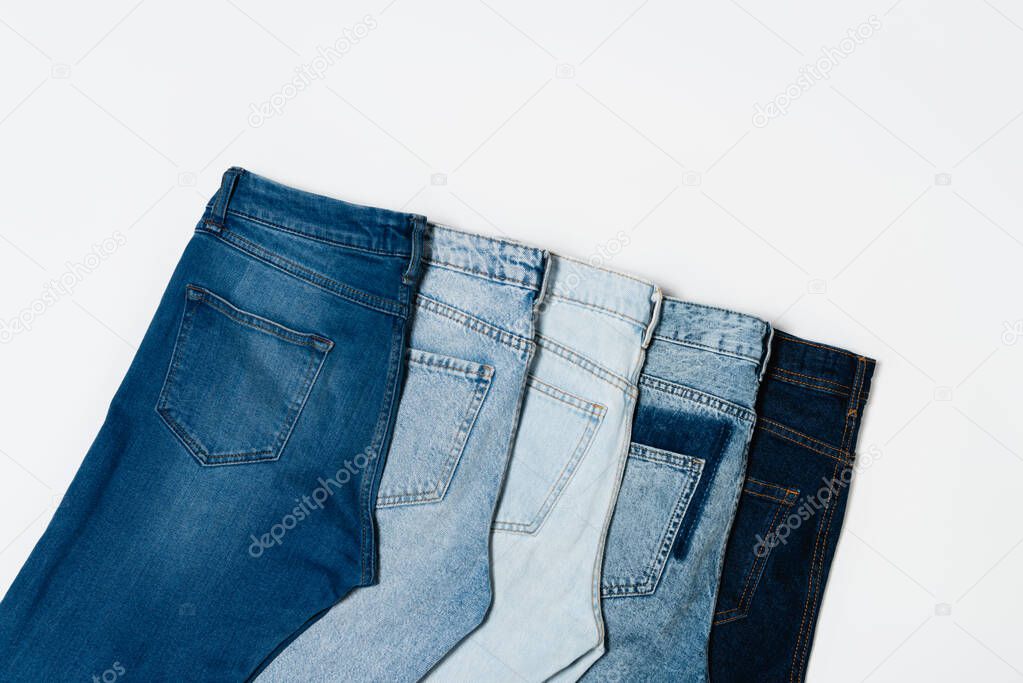 flat lay of different blue jeans on white background, top view