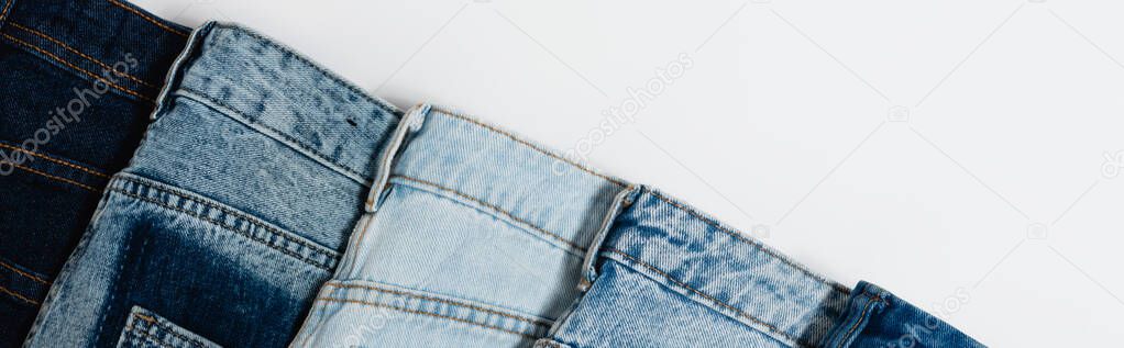 diagonal row of different jeans on white background, top view, banner