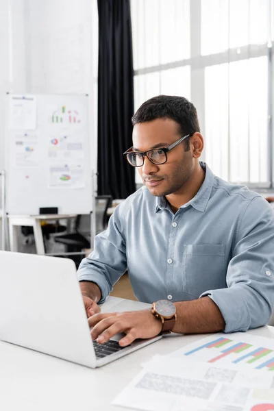 Indian Businessman Using Laptop Papers Charts Blurred Foreground — Stock Photo, Image