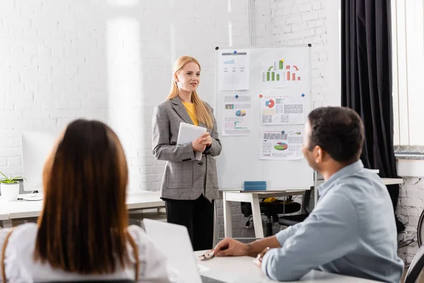 Smiling Businesswoman Digital Tablet Standing Flipchart Colleagues Blurred Foreground — Stock Photo, Image