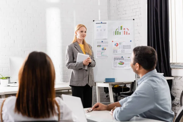 Lächelnde Geschäftsfrau Mit Digitalem Tablet Neben Flipchart Und Kollegen Verschwommenen — Stockfoto