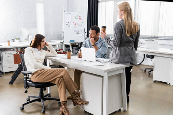 Multicultural business people holding coffee to go while working together in office 