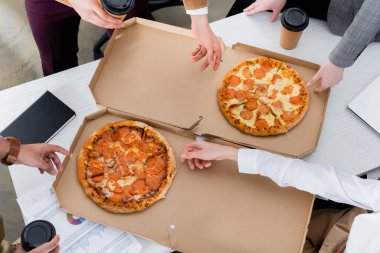 Ofiste öğle yemeği sırasında pizza yiyen iş adamlarının görüntüsü. 