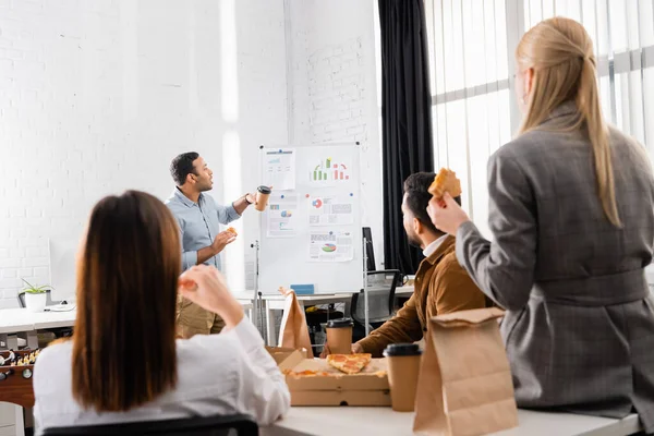 Indian Businessman Pizza Coffee Standing Flipchart Colleagues Blurred Foreground — Stock Photo, Image