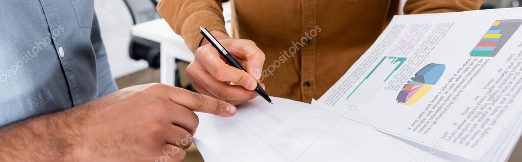 Cropped view of businessman pointing with finger near colleague with papers and pen in office, banner 