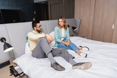 Bir bardak şarapla gülümseyen kadın otelde Müslüman erkek arkadaşının yanında oturuyor. 