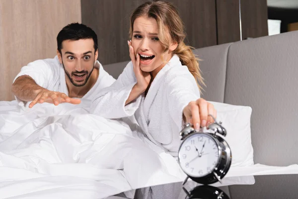 Worried Woman Muslim Man Looking Alarm Clock Blurred Foreground Hotel — Stock Photo, Image