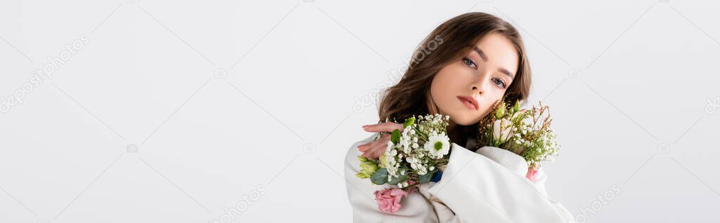Brunette woman posing with flowers in sleeves isolated on grey, banner 