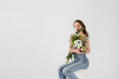 Shirtless model holding flowers on chair isolated on grey with copy space 