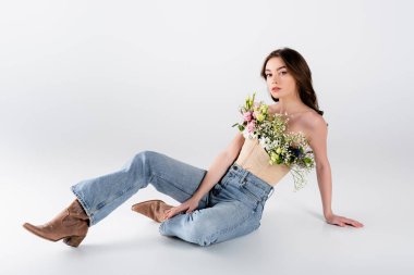 Gri arka planda oturan, bluzlu, genç ve şık bir model.