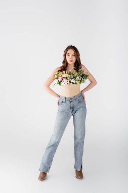 Bluzunda çiçekler olan şık bir model ve gri arka planda kalçaları olan eller.