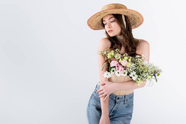 Güneş şapkalı model, gri üzerinde izole edilmiş çiçeklerle fotokopi alanı ile poz veriyor.