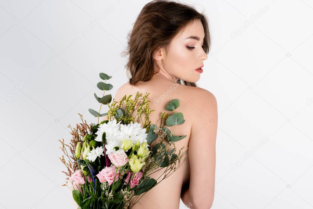 Back view of shirtless brunette model holding flowers near back isolated on grey 