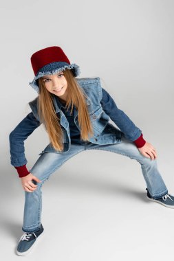 Şık kot elbiseli ve gri şapkalı neşeli kız.