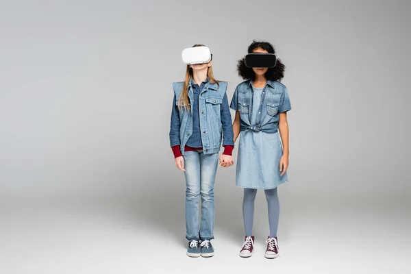 Trendy Interracial Girls Headsets Holding Hands While Standing Grey — Stock Photo, Image