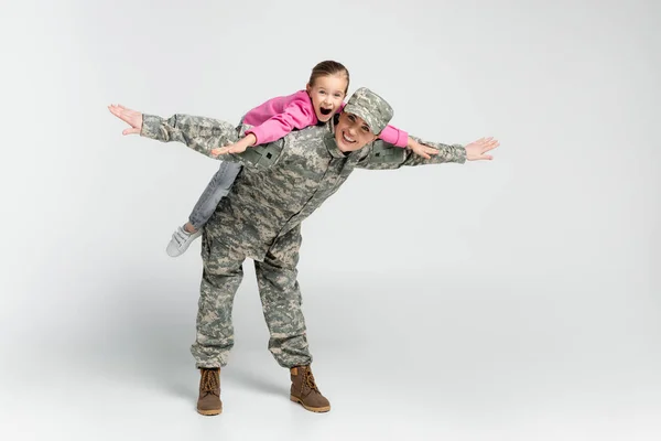 Amazed Girl Piggybacking Mother Camouflage Grey Background — Stock Photo, Image