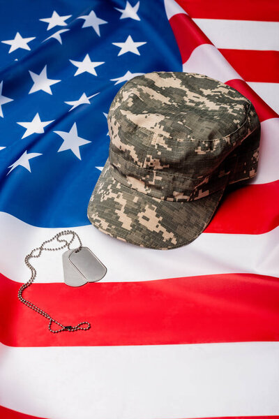 Military cap and dog tags on american flag 