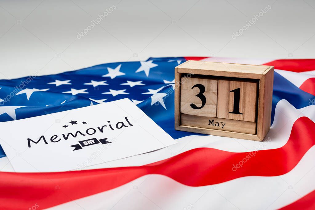 Card with memorial day lettering, wooden calendar and american flag on grey background 