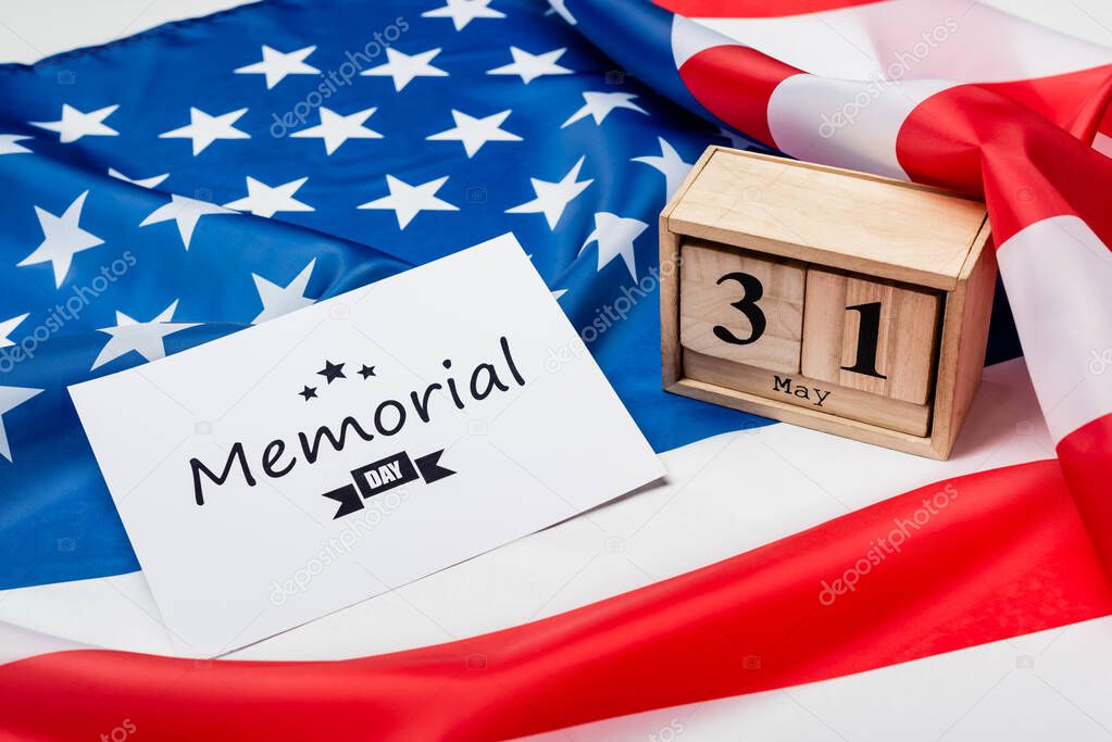 Wooden calendar and card with memorial day lettering on american flag on grey background 