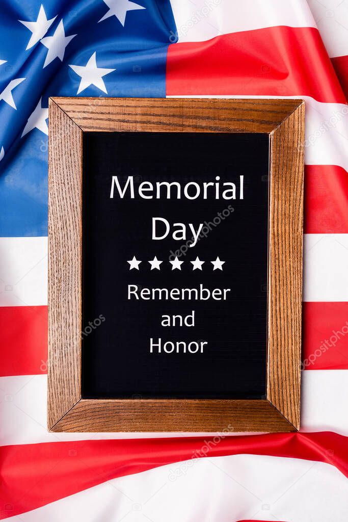 Top view of memorial day remember and honor lettering on chalkboard on american flag 