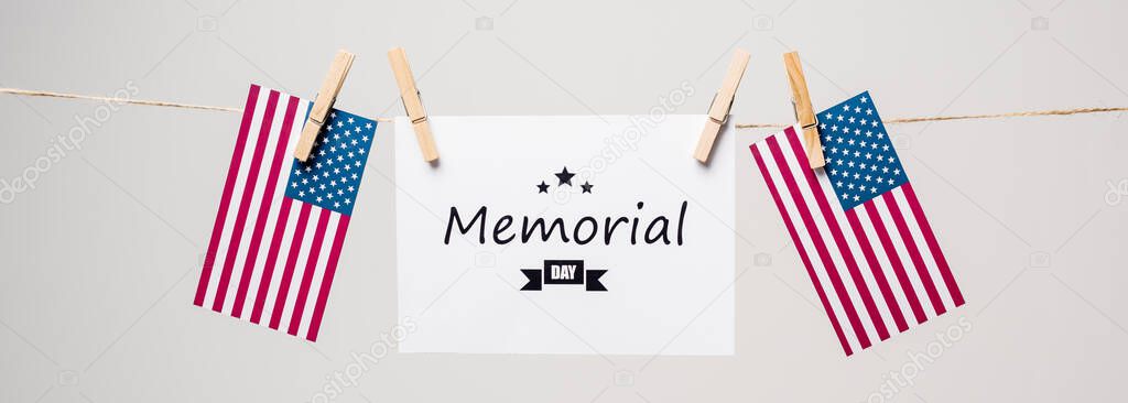 Memorial day lettering on card near american flags on rope isolated on grey, banner 