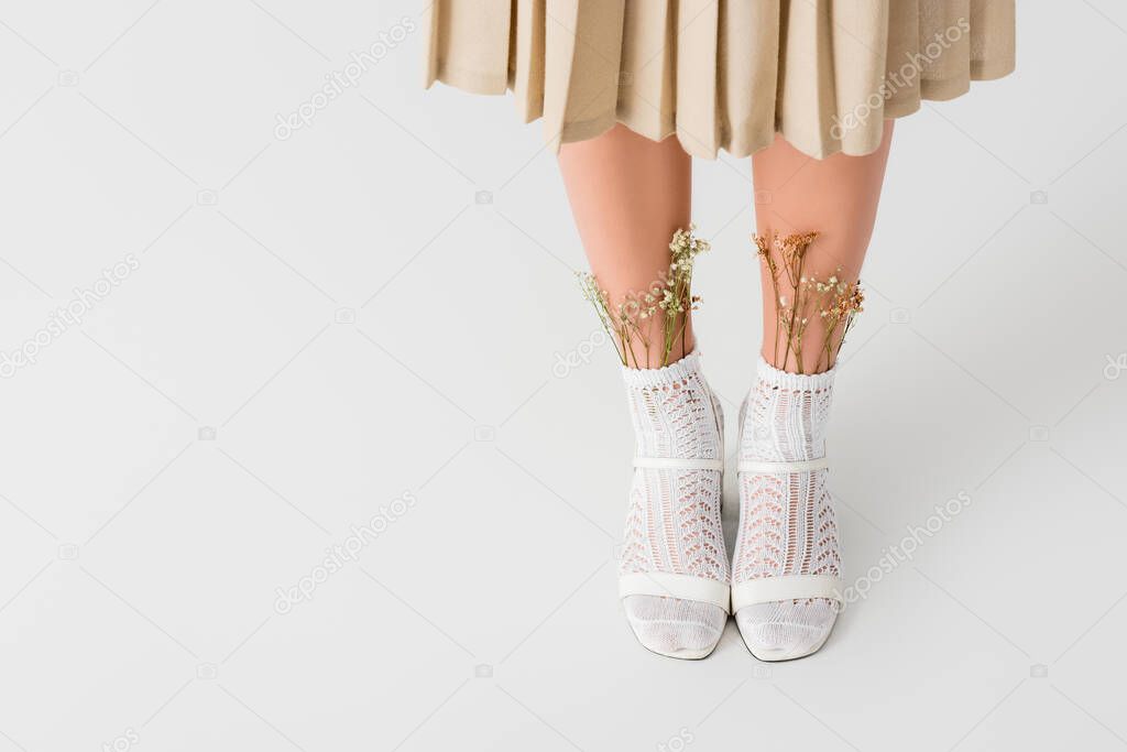 cropped view of woman in socks with flowers, skirt and heeled shoes standing on white