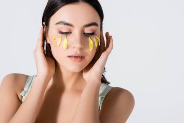 Yüzünde sarı taç yaprakları olan esmer genç bir kadın.