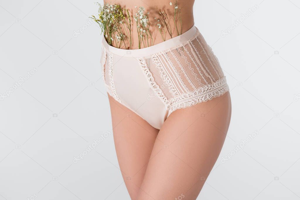 cropped view of young woman in panties with blooming flowers isolated on white