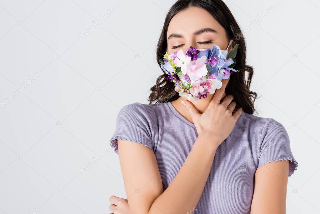 young model in crop top and medical mask with blooming flowers posing isolated on white