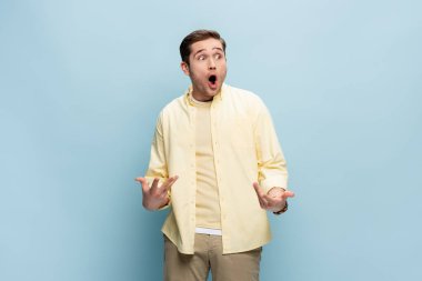 Şok olmuş genç adam başka tarafa bakıyor ve maviye işaret ediyor.