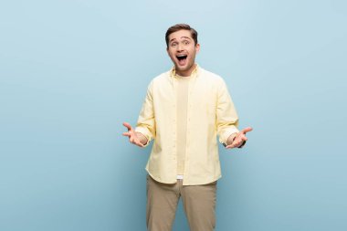 Heyecanlı adam kameraya bakıyor ve maviye işaret ediyor.