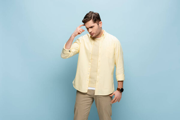 застенчивый молодой человек смотрит вниз, думая о синем