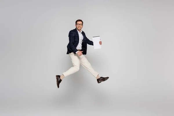 Comprimento Total Empresário Alegre Óculos Segurando Papel Enquanto Saltando Cinza — Fotografia de Stock