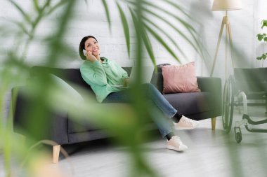 Evde tekerlekli sandalye ve dizüstü bilgisayarın yanında konuşan gülümseyen bir serbest yazar. 