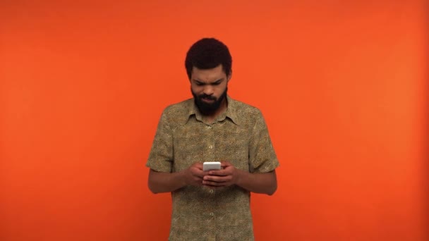 Homem Afro Americano Descontente Mensagens Smartphone Isolado Laranja — Vídeo de Stock