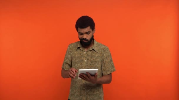 Homme Afro Américain Insatisfait Utilisant Tablette Numérique Isolé Sur Orange — Video