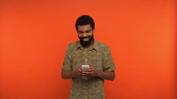 Sorridente Afro Americano Homem Mensagens Texto Smartphone Isolado Laranja — Vídeo de Stock